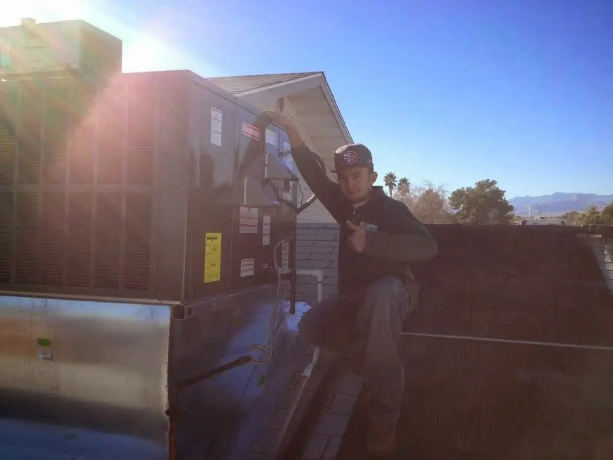 HVAC technician performing Heat Pump Repair on a rooftop unit in Aston